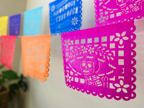 Multicolor Día de los Muertos papel picado banner with skull and floral cutouts